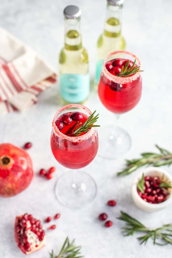 Prosecco drink with cranberries and rosemary in a glass flute